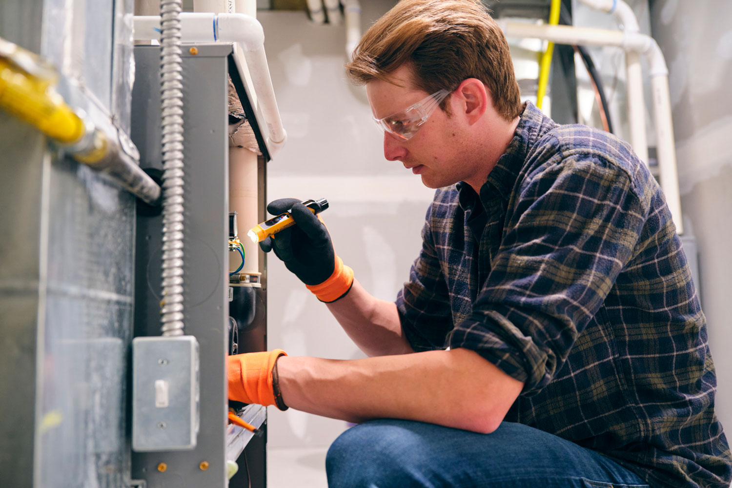 A-repairman-working-inside-a-home-repairing-a-furnace